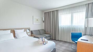 Una habitación de hotel con cama, sofá, escritorio y silla.