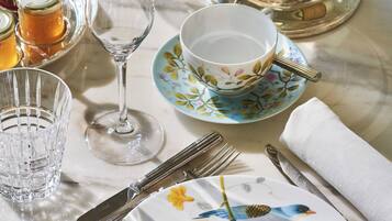 A table set with fine china, silverware, and scones, suggesting a formal dining experience.