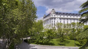 A large, historic building with classical architecture, surrounded by lush greenery and a well-maintained lawn.