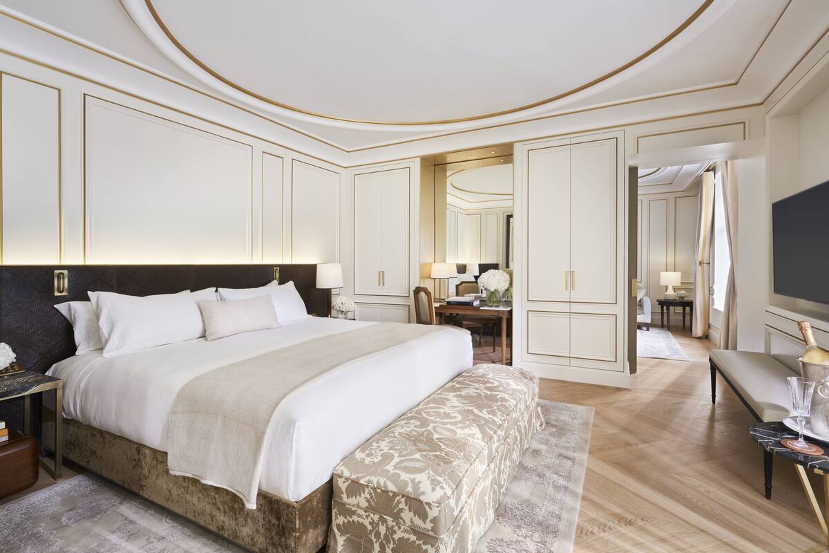 A spacious bedroom with a large bed, a bedside table, a desk, and a television.