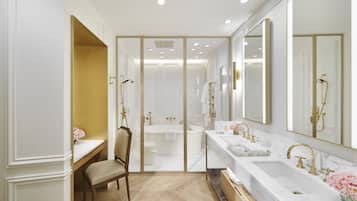 Un baño lujoso con un espejo grande, dos lavamanos, una bañera y un tocador.