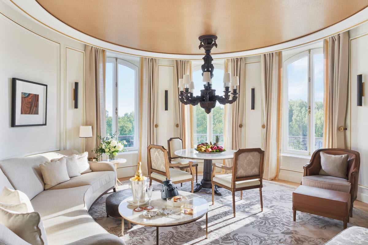 A luxurious living room with a round table, elegant chairs, and a chandelier.