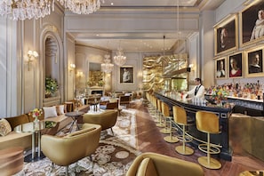 A luxurious bar area with high stools, a bartender, and a bar counter.