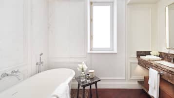 A bathroom with a bathtub, a vanity with a mirror, and a window.