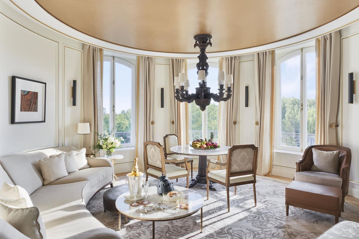 A luxurious living room with a round table, elegant chairs, and a chandelier.
