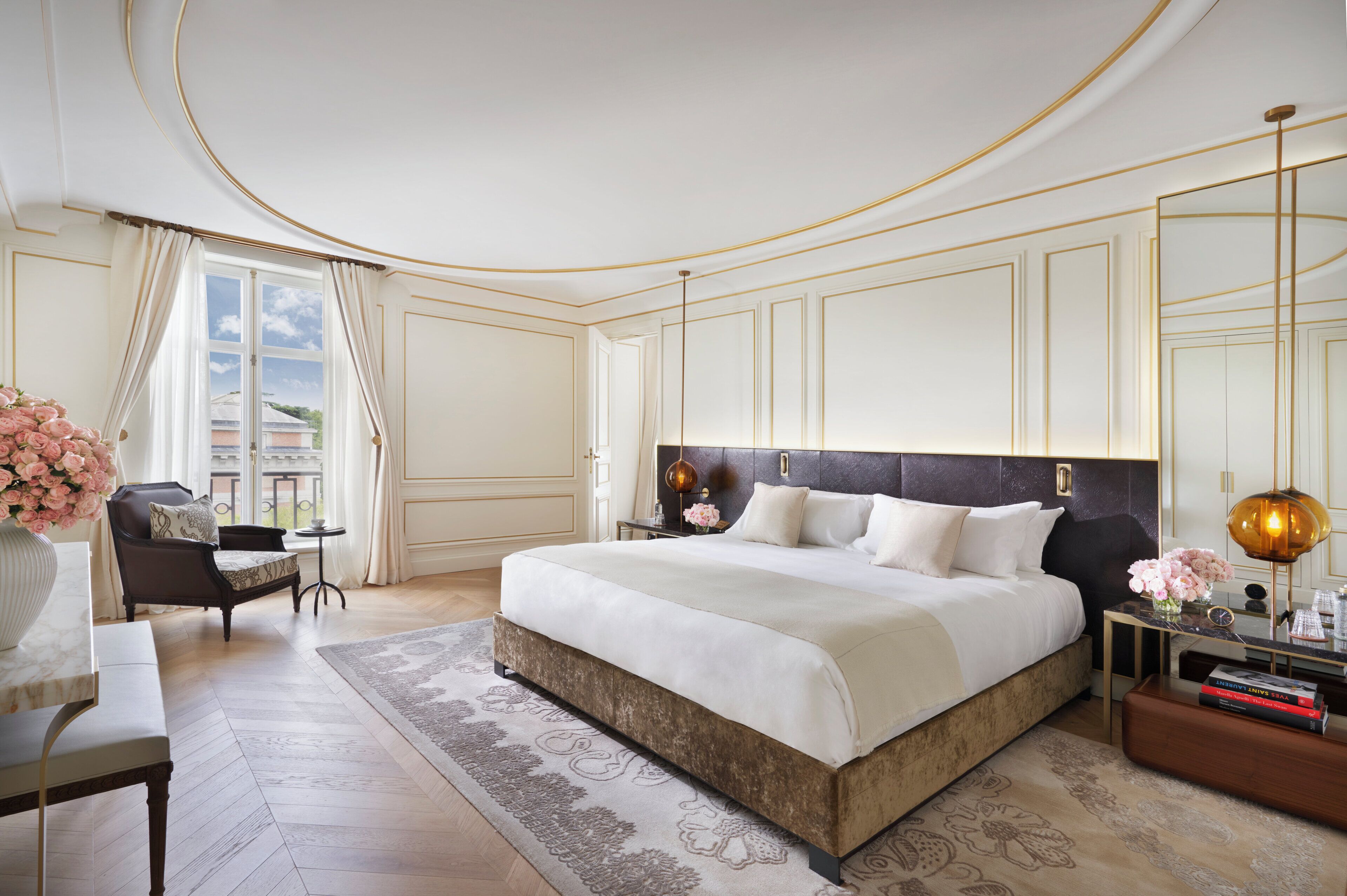 Un dormitorio amplio con una cama grande, una zona de estar con una silla y una mesa, y vistas al exterior a través de una ventana.