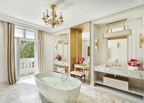 A luxurious bathroom with a freestanding bathtub, marble countertops, and a large mirror.