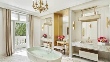 Een luxe badkamer met een vrijstaand bad, marmeren aanrechtbladen en een grote spiegel.