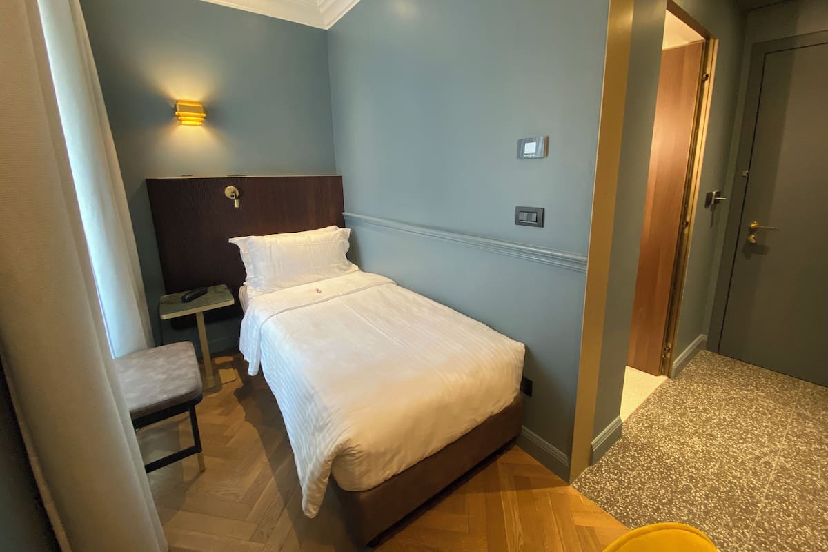A hotel room with a bed, bedside table, and a chair.