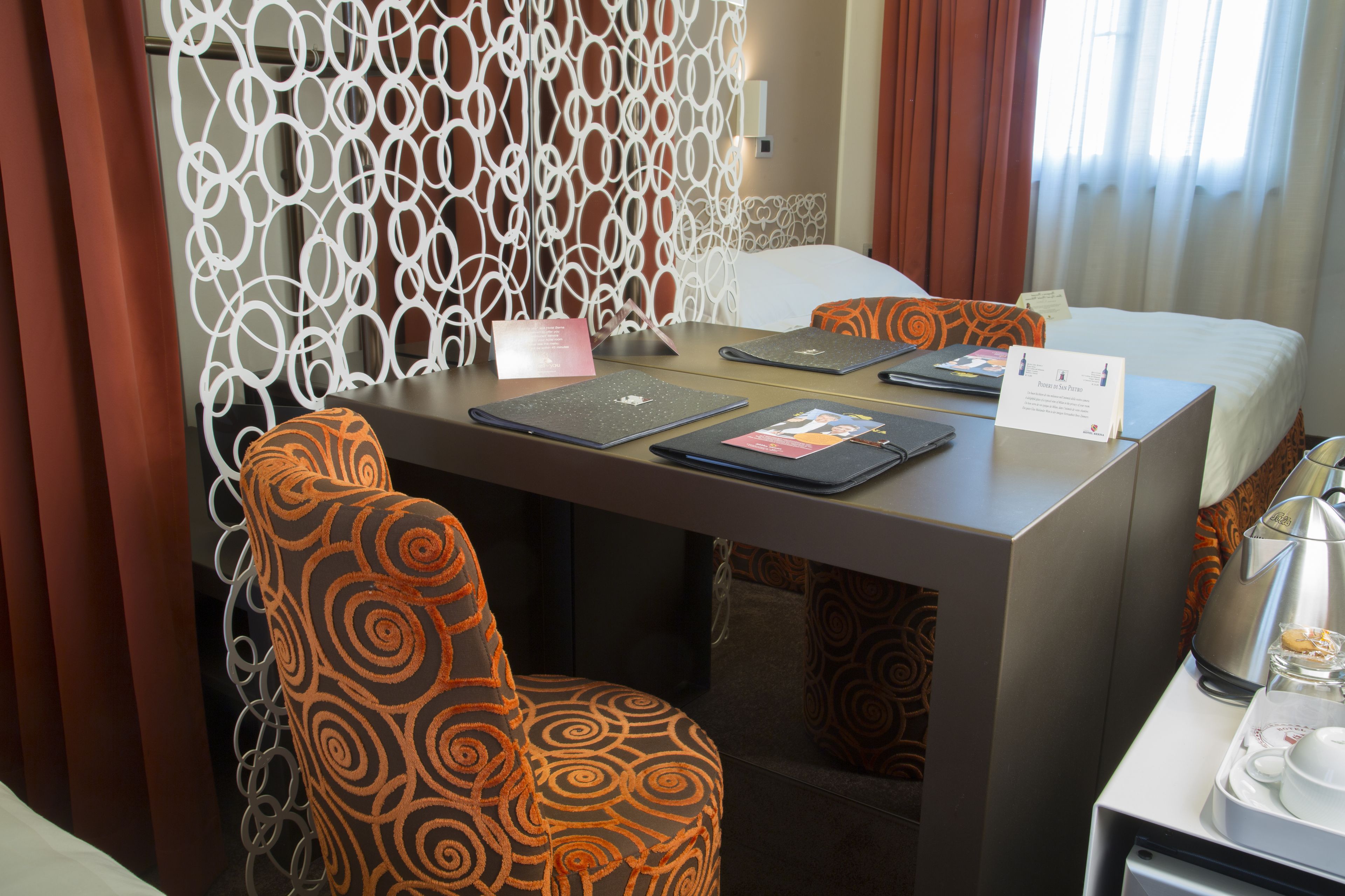 A hotel room with a bed, a desk with a laptop, a chair, and a coffee maker.