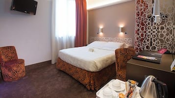 Habitación de hotel con cama, escritorio con una computadora portátil, televisor montado en la pared y un panel decorativo.