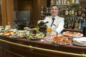 A bar area with a variety of food items and a bartender pouring a drink.