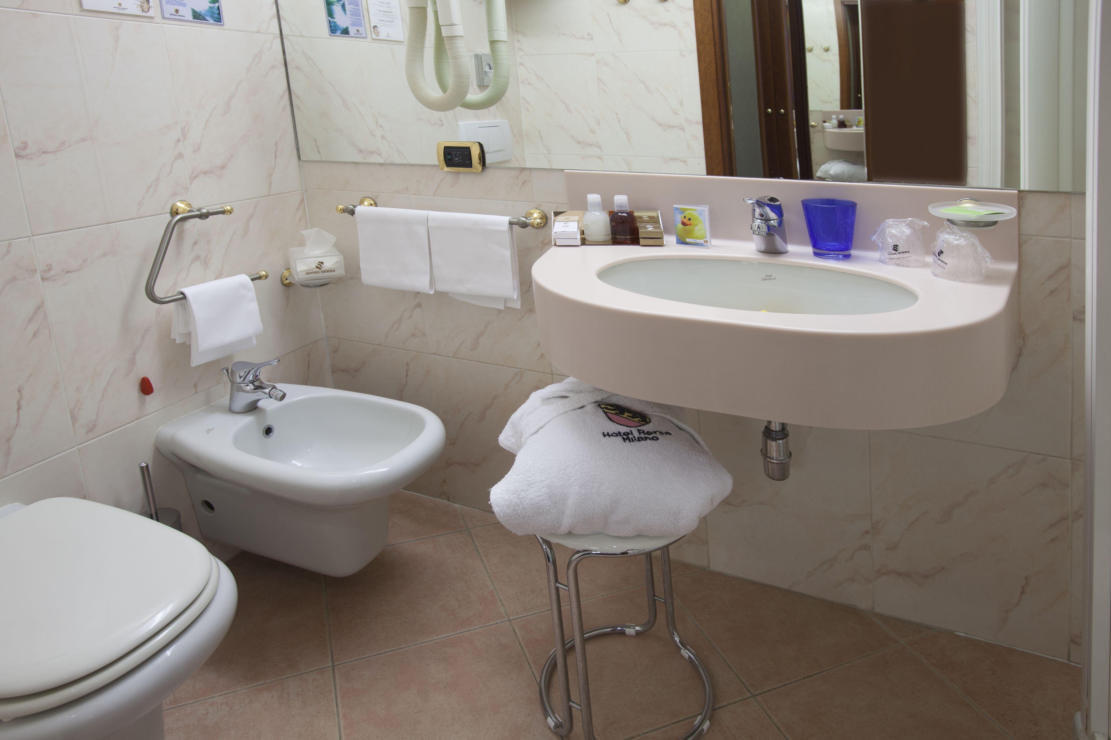 A bathroom with a toilet, bidet, sink, and a mirror.