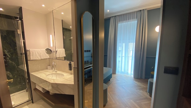 A modern bathroom with a glass shower enclosure, a large mirror, and a vanity with a sink and towel rack.