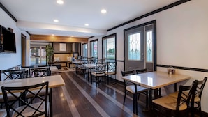 A modern restaurant with wooden flooring, black-framed windows, and a variety of seating arrangements including tables and booths. - Days Inn by Wyndham Vernon (Vernon)