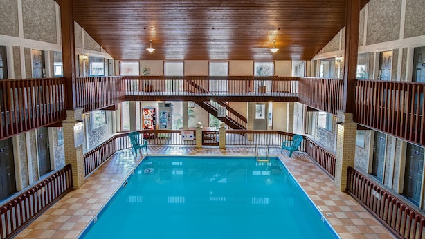 An indoor swimming pool with a wooden deck, multiple levels with railings, and a view of the outside through large windows. - Days Inn by Wyndham Vernon (Vernon)