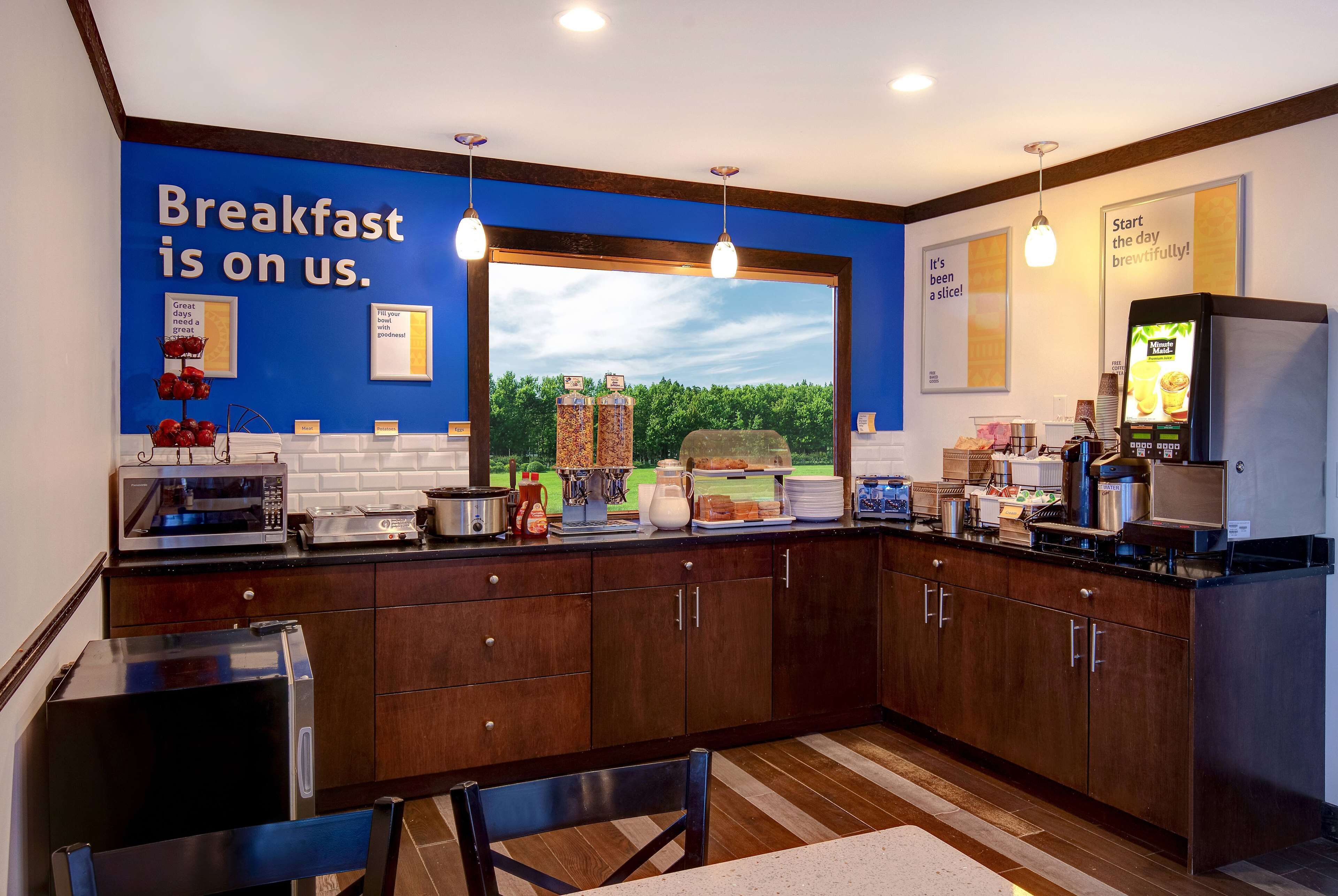 A modern kitchen with a large window, wooden cabinets, and a breakfast bar.