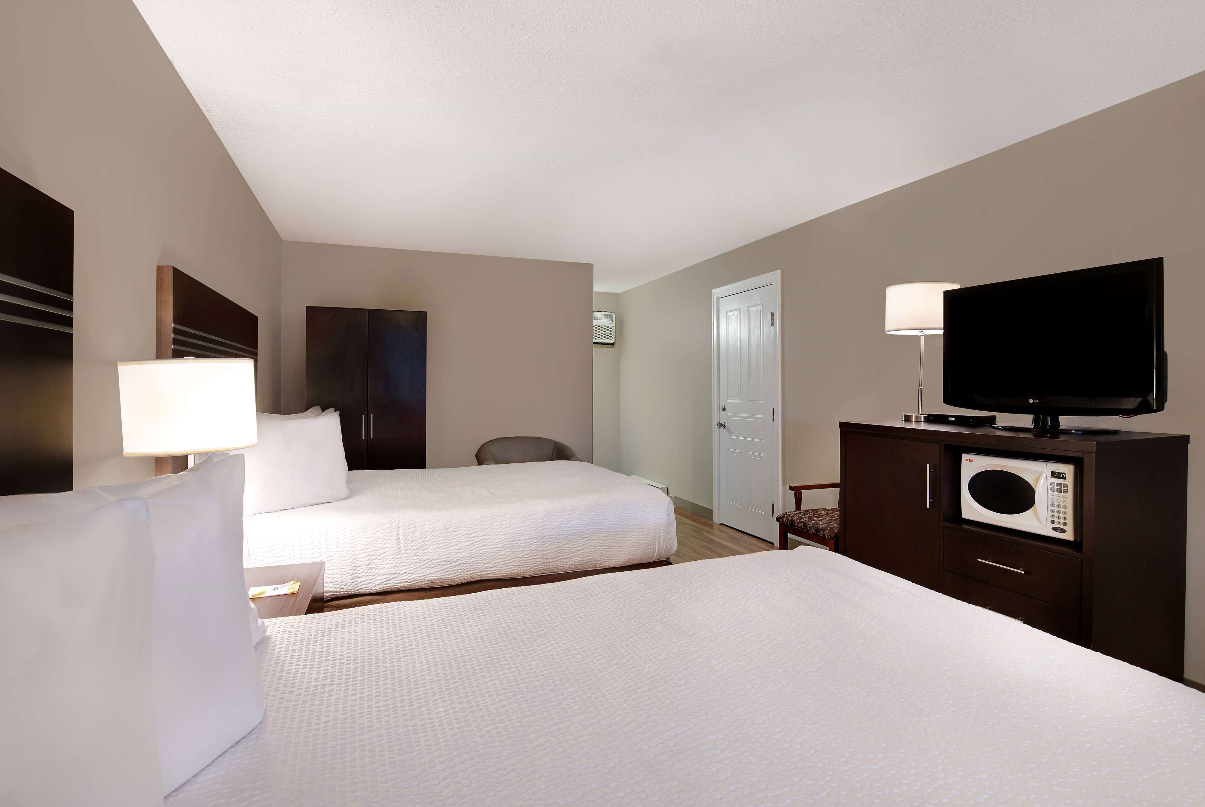 Una habitación de hotel con dos camas, televisión, microondas y lámpara.