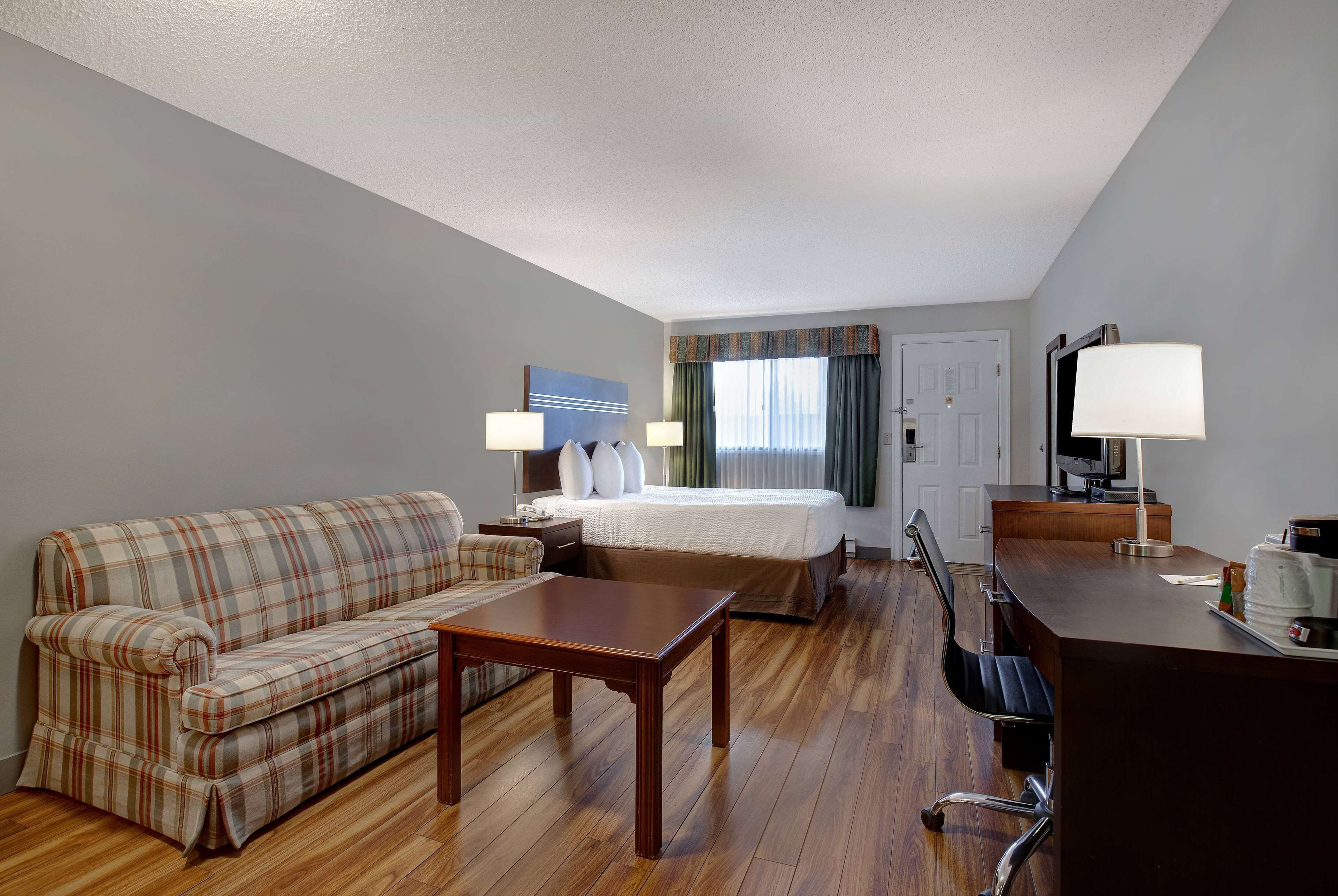 Een hotelkamer met een bed, een bank, een bureau en een stoel.