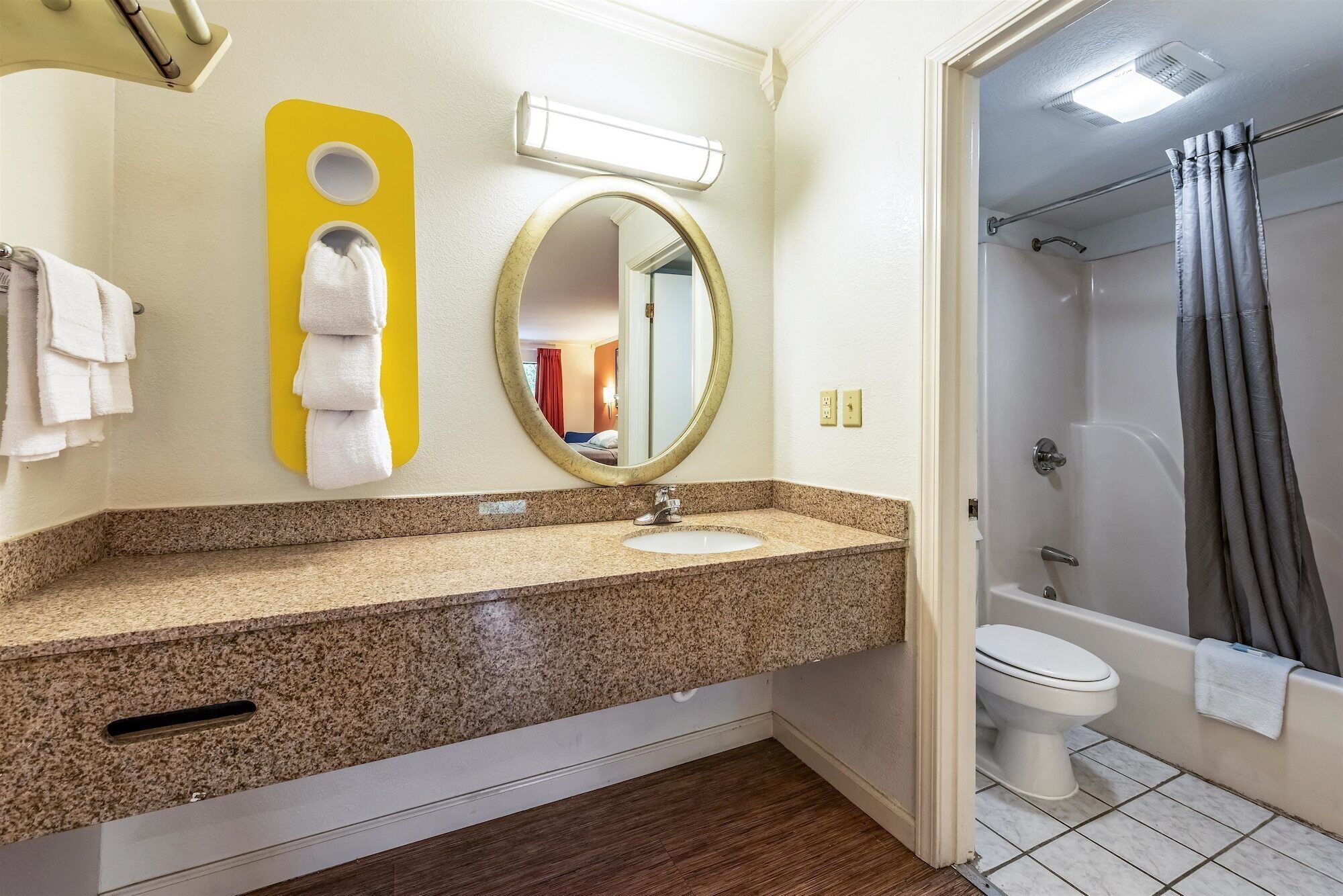 Une salle de bain avec un comptoir en granit, un lavabo, un miroir et un espace douche.