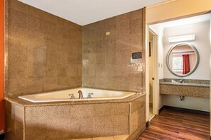 Een badkamer met een vrijstaand bad, een wastafel met spiegel en een bordje waarop staat dat er geen schuimbadproducten gebruikt mogen worden.