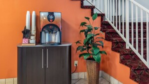 Une machine à café, un meuble et une plante en pot, le tout placé dans un coin.