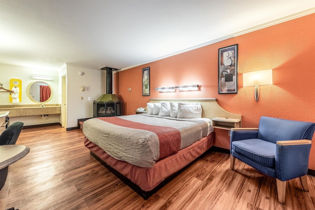 Une chambre d’hôtel avec un lit, une chaise, un bureau et une cheminée.