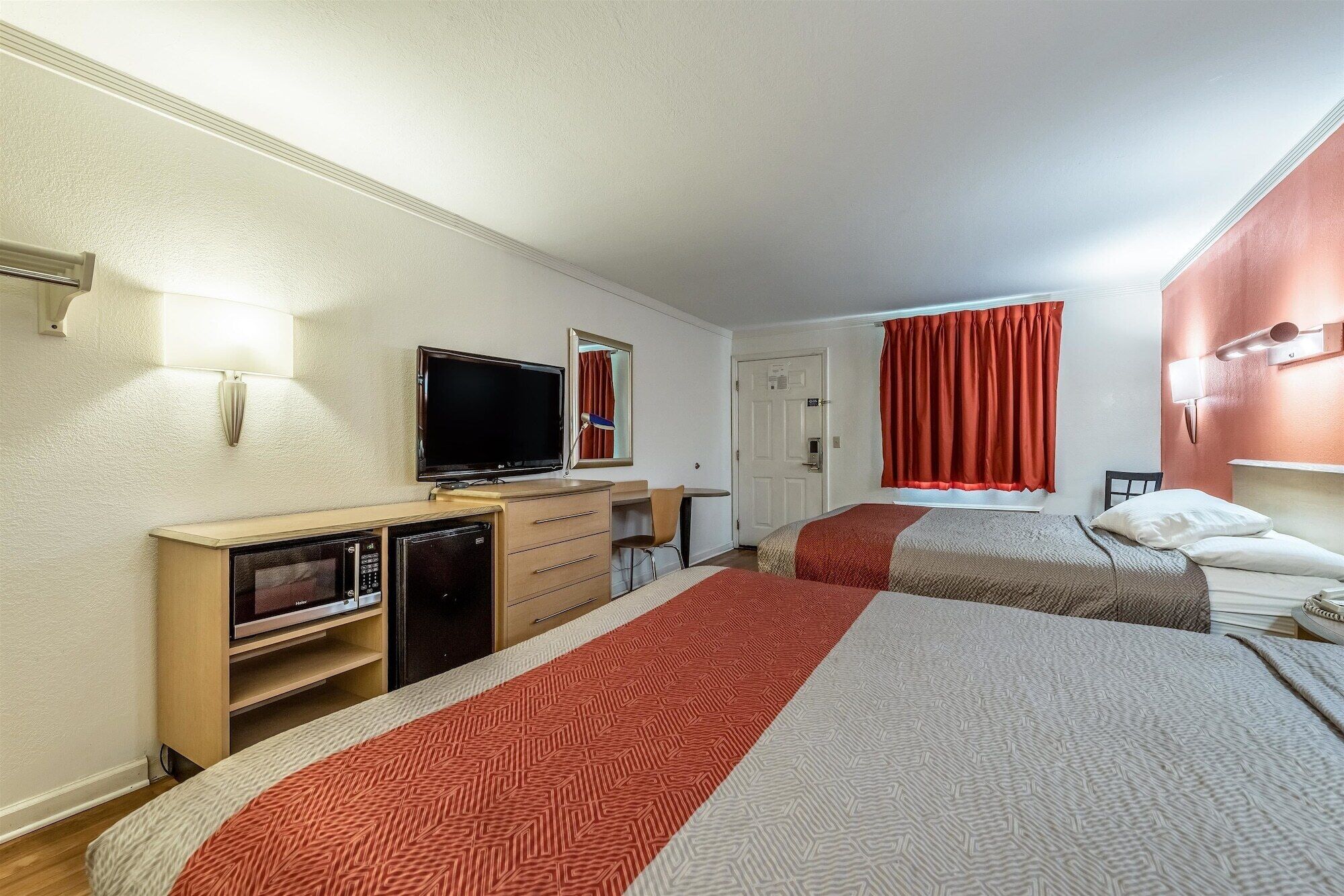Habitación de hotel con dos camas, televisión, escritorio y armario.