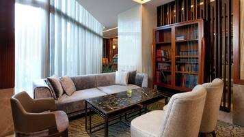 Een moderne woonkamer met een bank, fauteuils, een salontafel en een boekenkast.