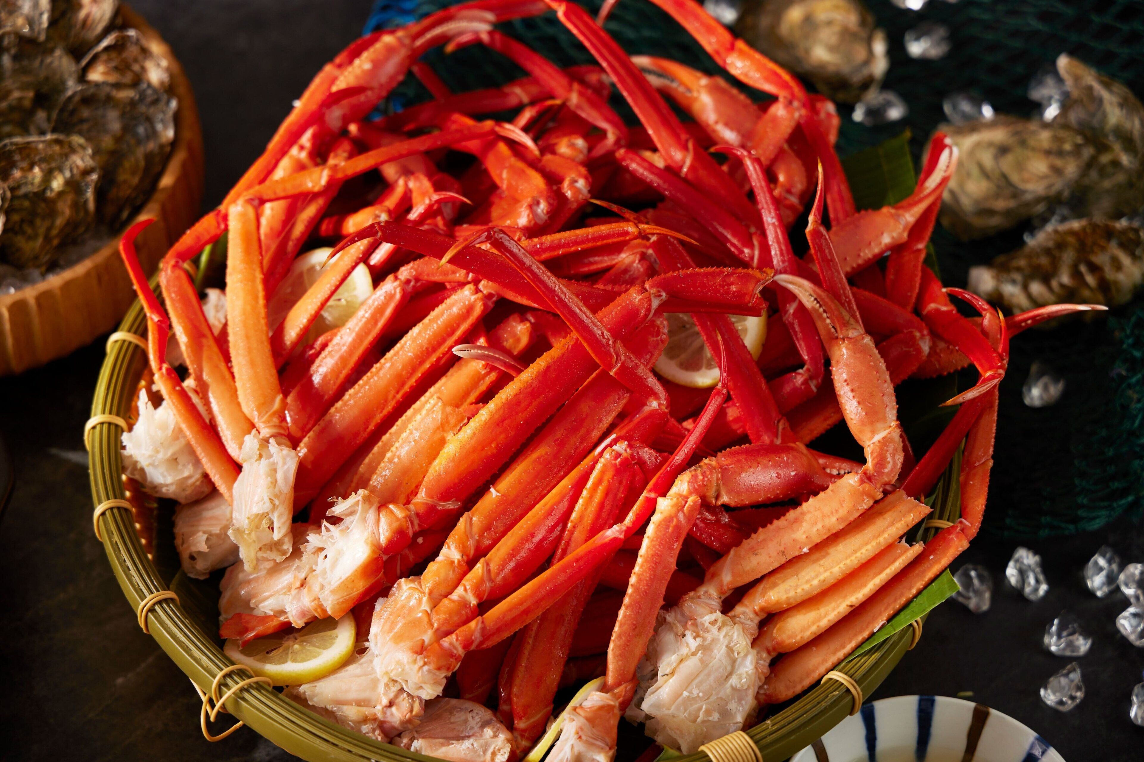 A basket filled with cooked crab legs and lemon slices.