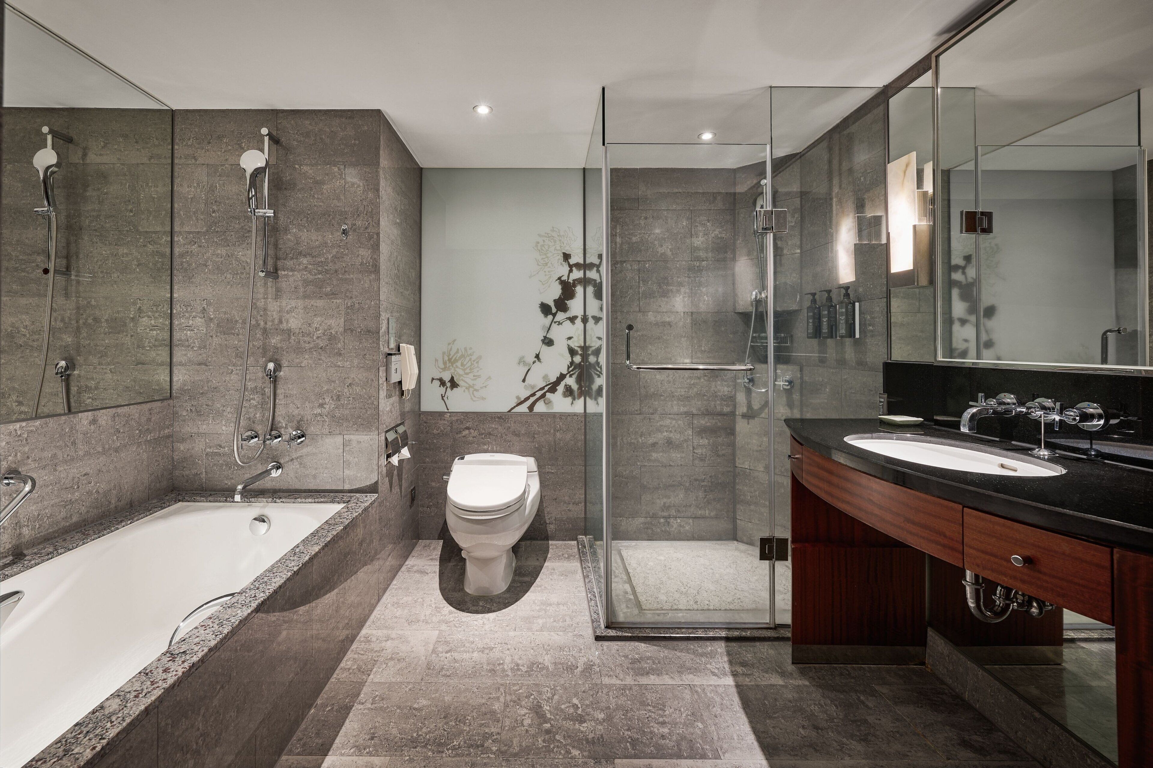 Une salle de bain moderne avec une baignoire sur pieds, une douche à parois de verre, des toilettes et un meuble-lavabo avec un miroir.