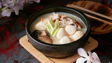 Un tazón de sopa con tofu y champiñones sobre una tabla de madera.