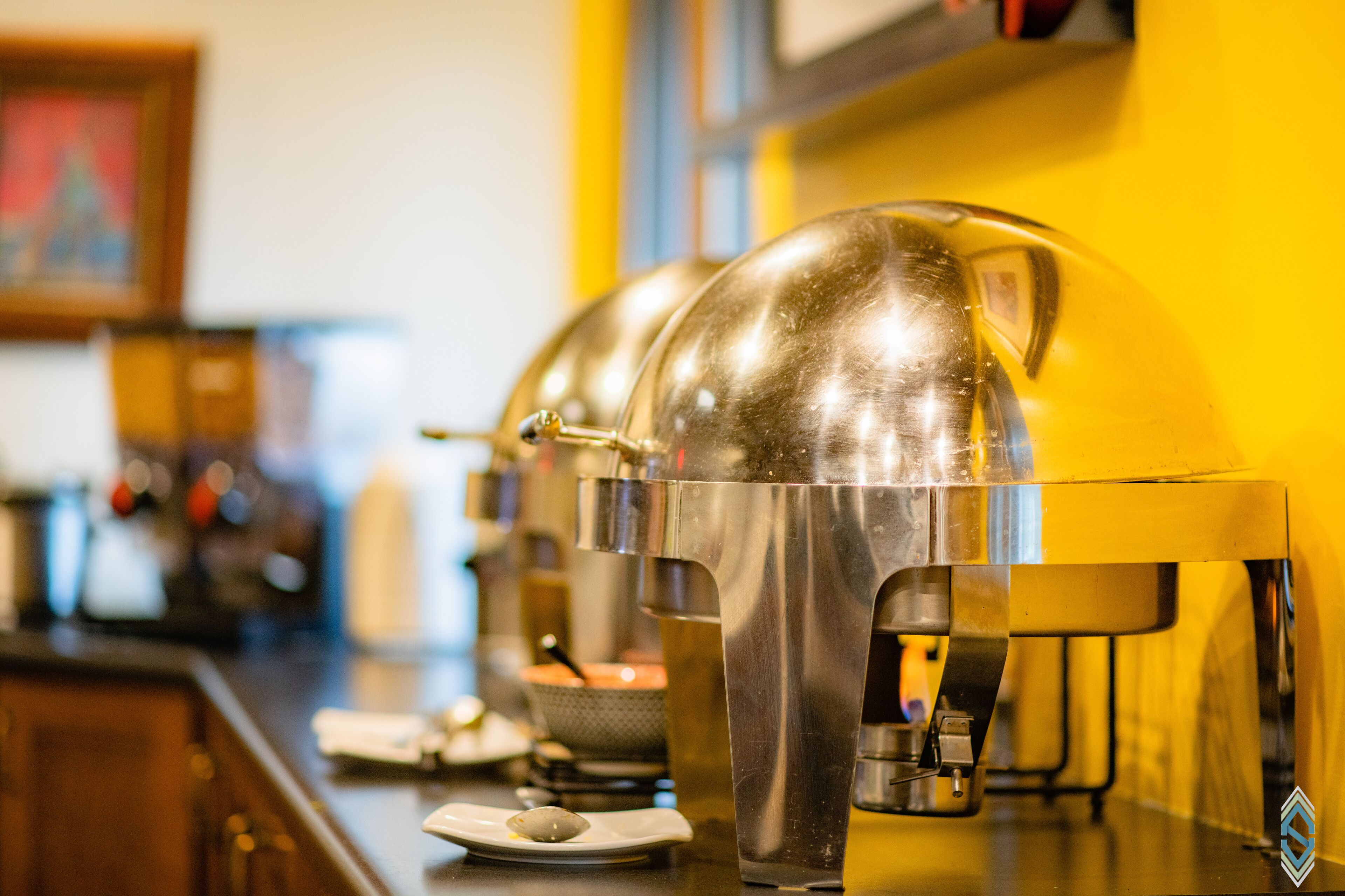 A row of stainless steel coffee machines with transparent drip trays on a bar counter.