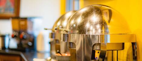 Una hilera de máquinas de café de acero inoxidable con bandejas de goteo transparentes sobre una barra.