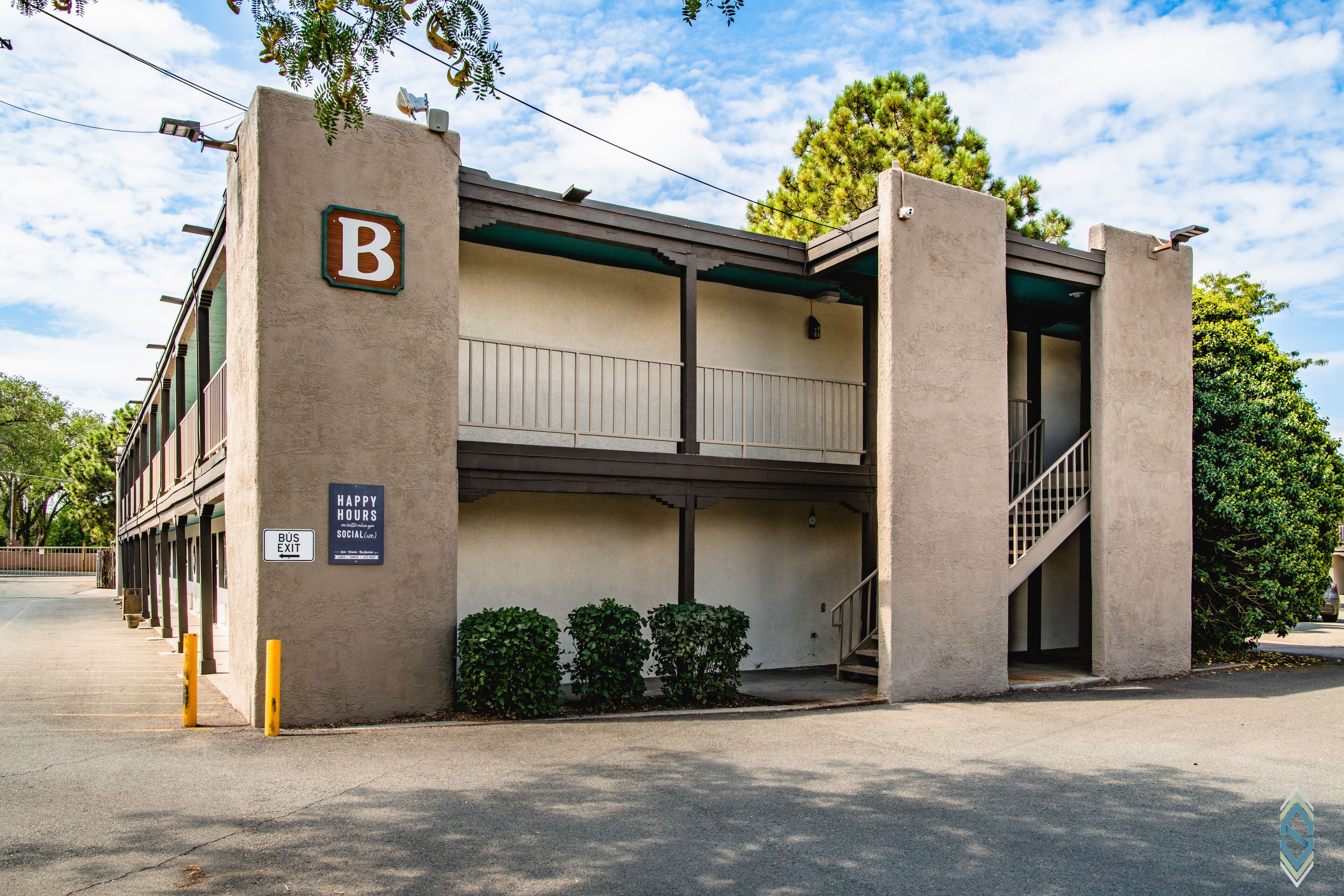 A building with a 'B' sign, a 'BUS EXIT' sign, and a staircase leading to an upper level.