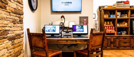 A workspace with two monitors, a clock, and a television displaying 'PAULDAVIS'.