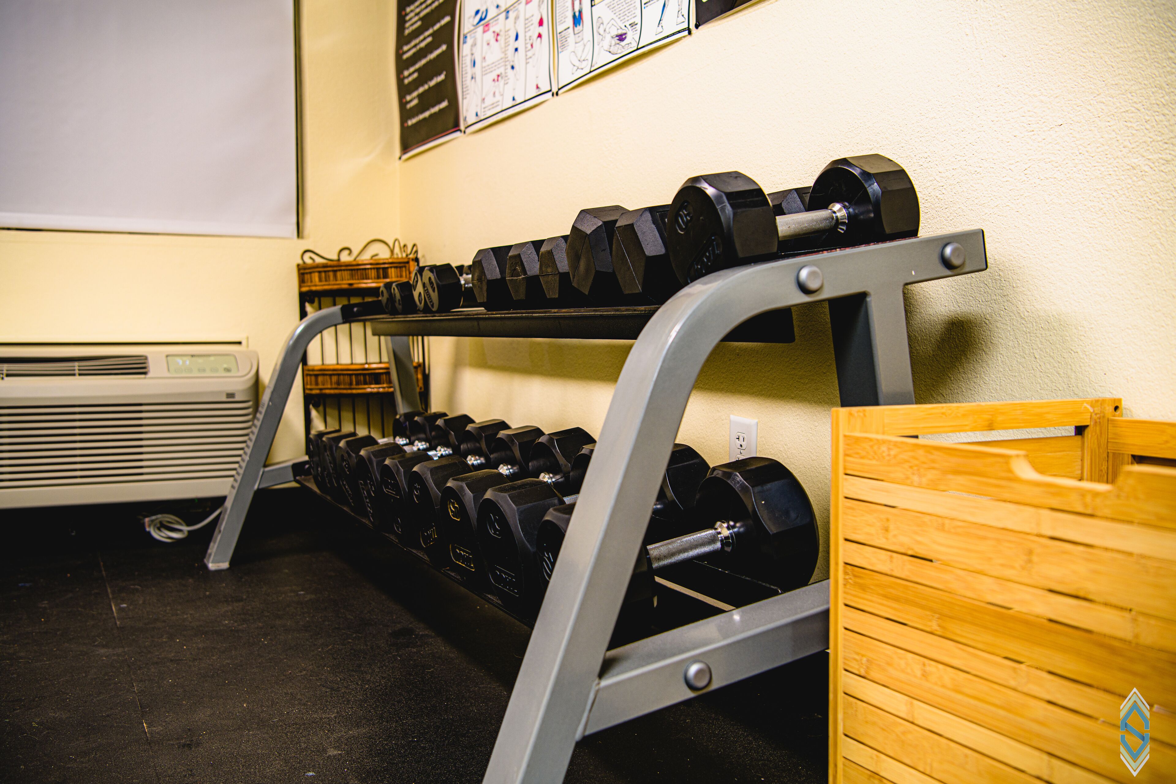 A gym with a rack of dumbbells and a wooden box.