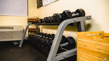 A gym with a rack of dumbbells and a wooden box.