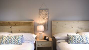 A double bed with a patterned pillow, a bedside lamp, and a phone on a wooden nightstand.
