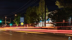A hotel named 'The Sage' with a signboard, trees, and a street with light trails.