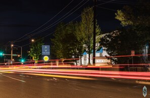 A hotel named 'The Sage' with a signboard, trees, and a street with light trails.
