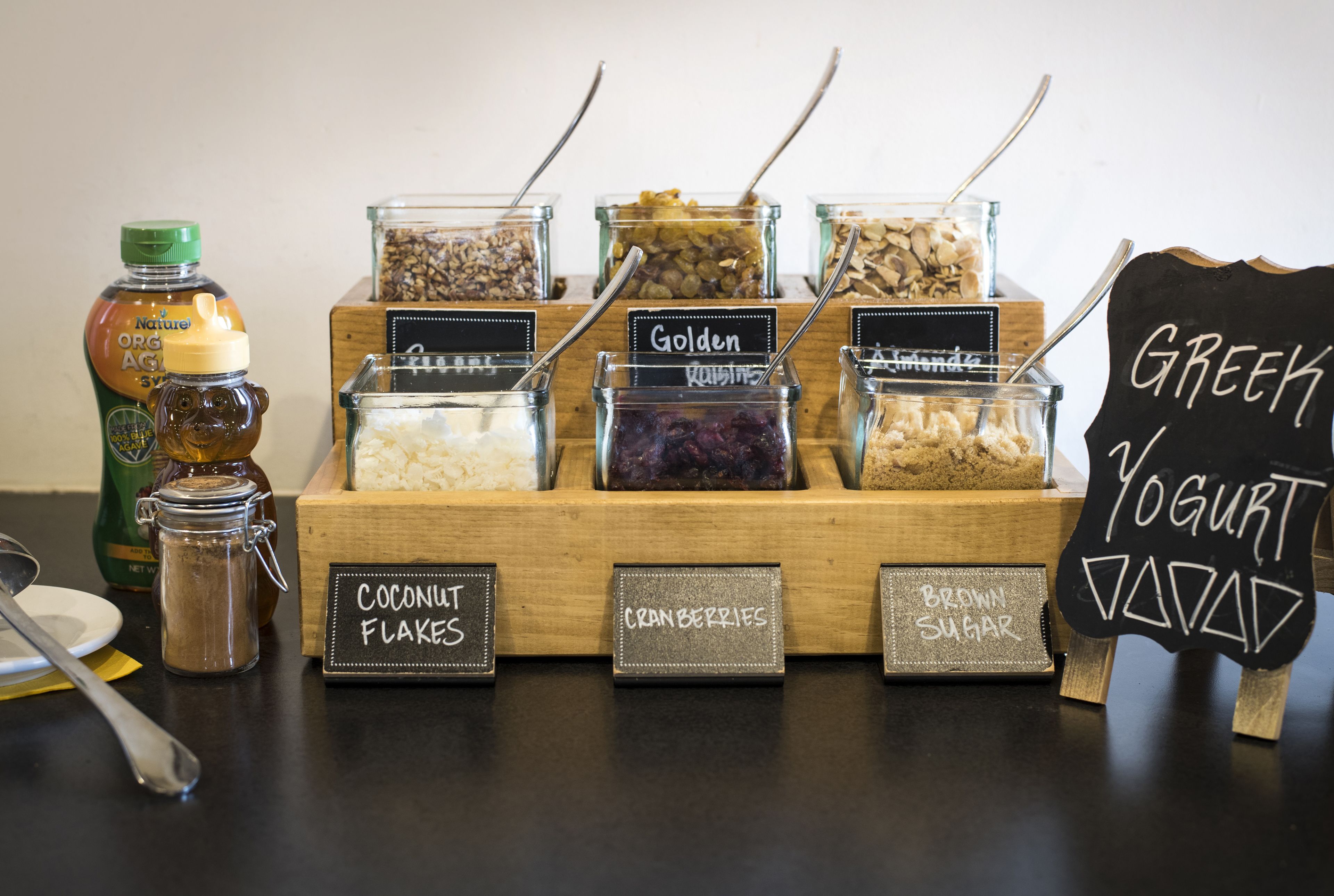 A food display with various jars labeled with items like coconut flakes, cranberries, and brown sugar.