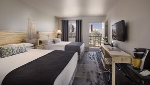 A hotel room with two beds, a desk, a TV, and a balcony with a view.