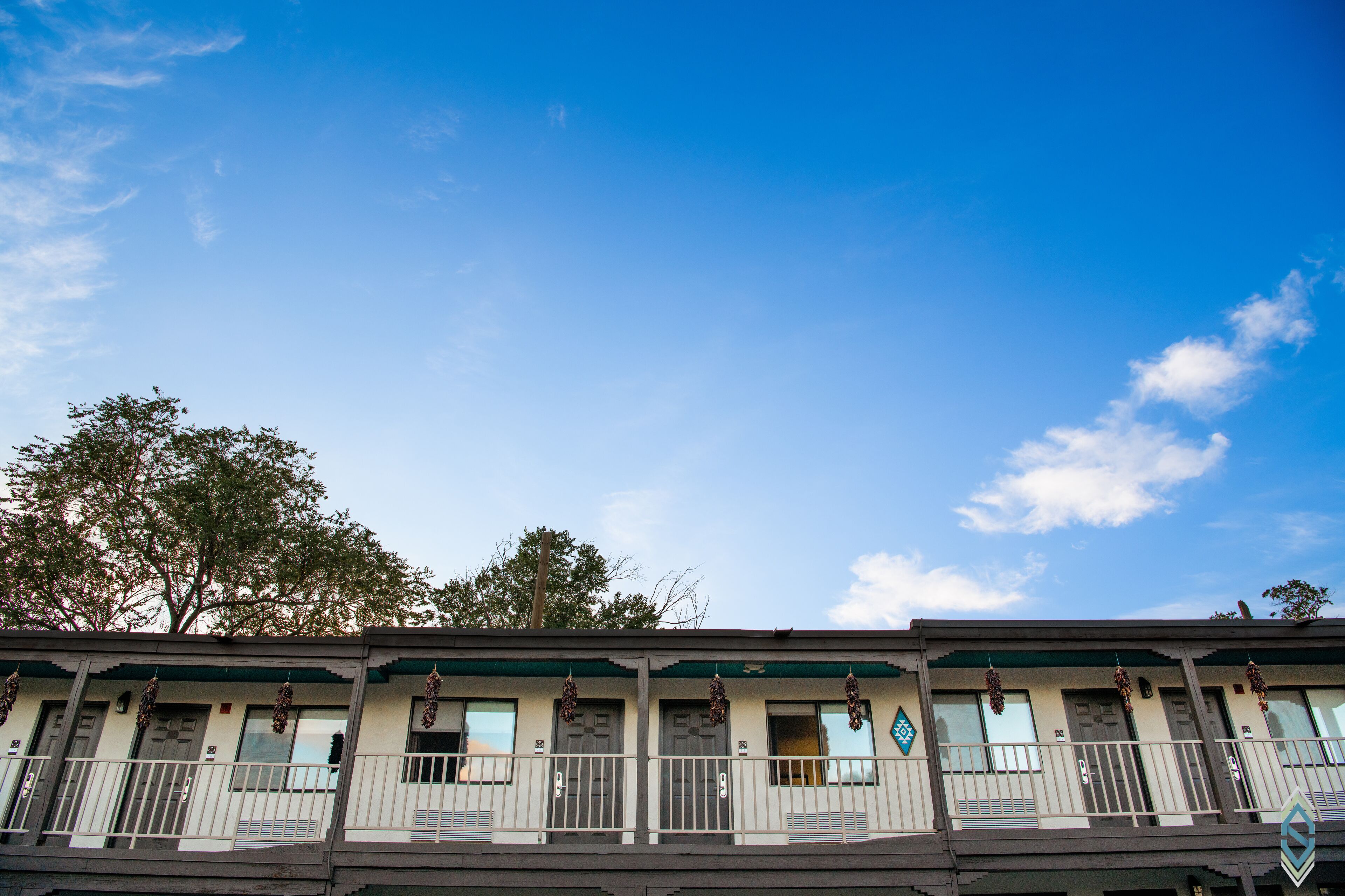 A row of motel-style buildings with balconies and hanging decorations.
