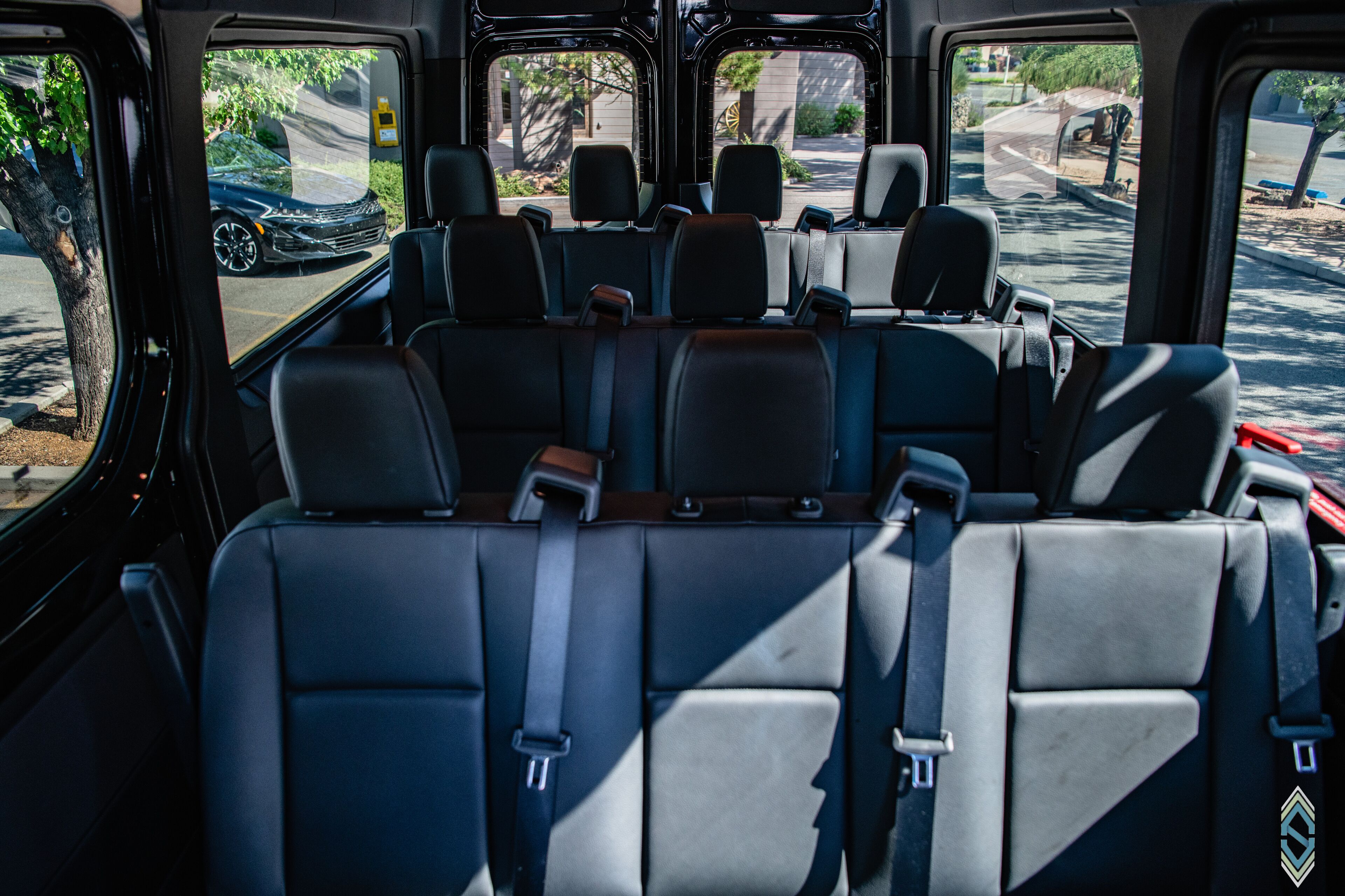 A vehicle interior with multiple rows of seats, a steering wheel, and a dashboard.