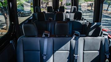 A vehicle interior with multiple rows of seats, a steering wheel, and a dashboard.