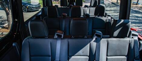 A vehicle interior with multiple rows of seats, a steering wheel, and a dashboard.