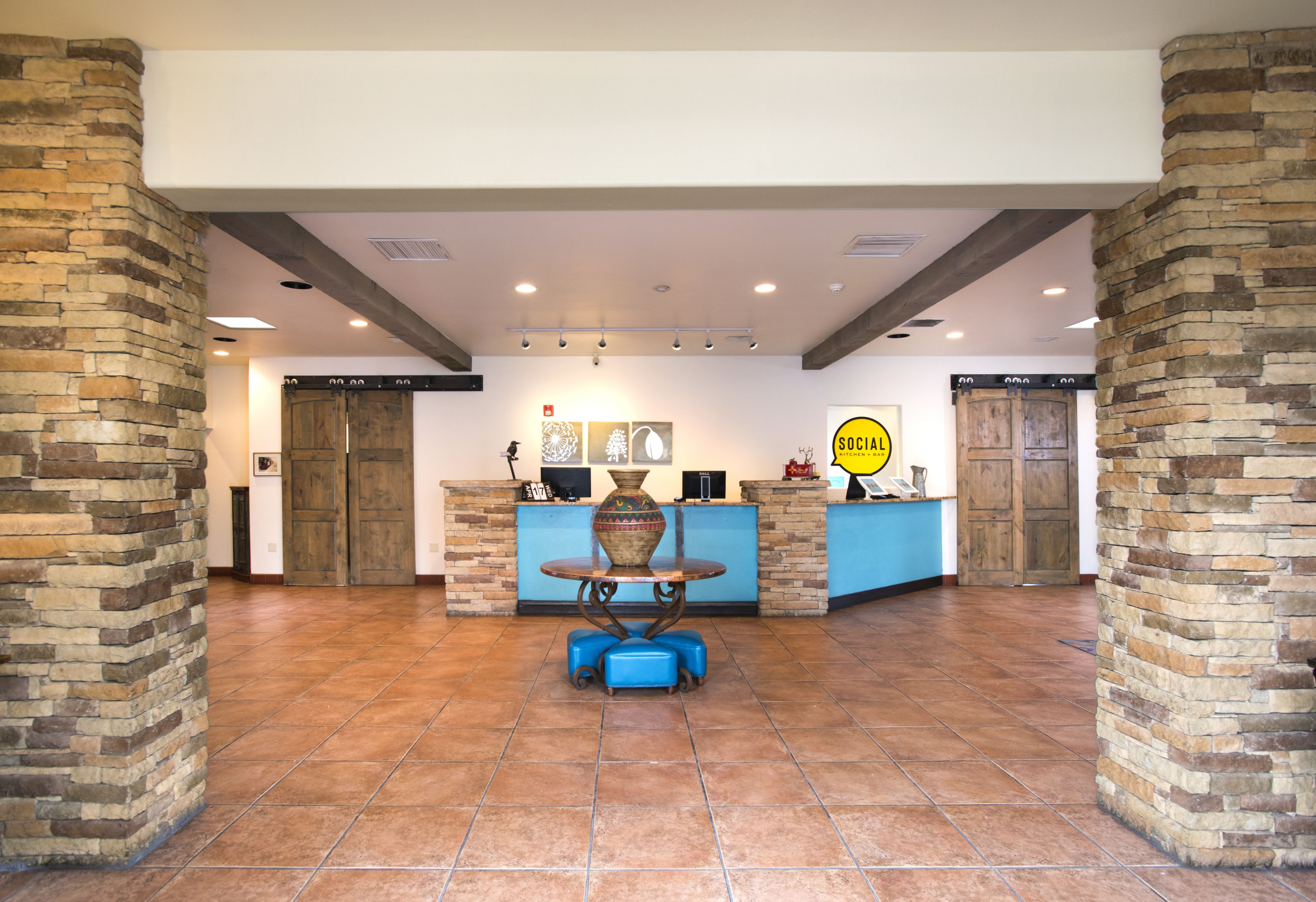A lobby with a reception desk, a blue sofa, and a stone pillar.