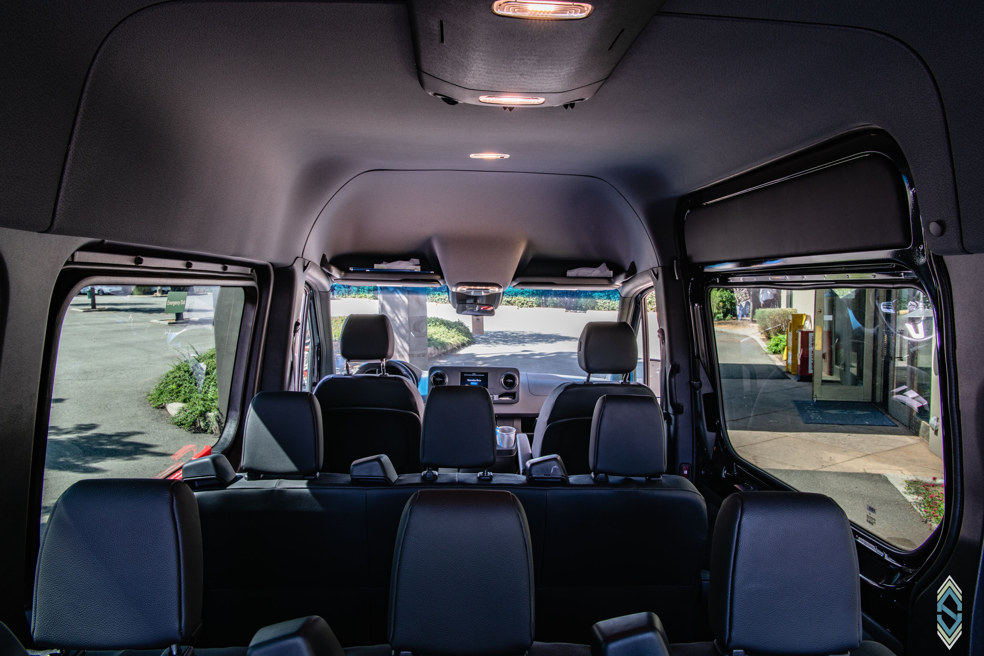 Interior de um veículo com fileira de assentos, volante e painel.