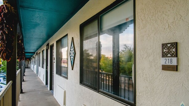 Un pasillo cubierto con ventanas grandes, un cartel con el número 218 y un elemento decorativo en la pared.